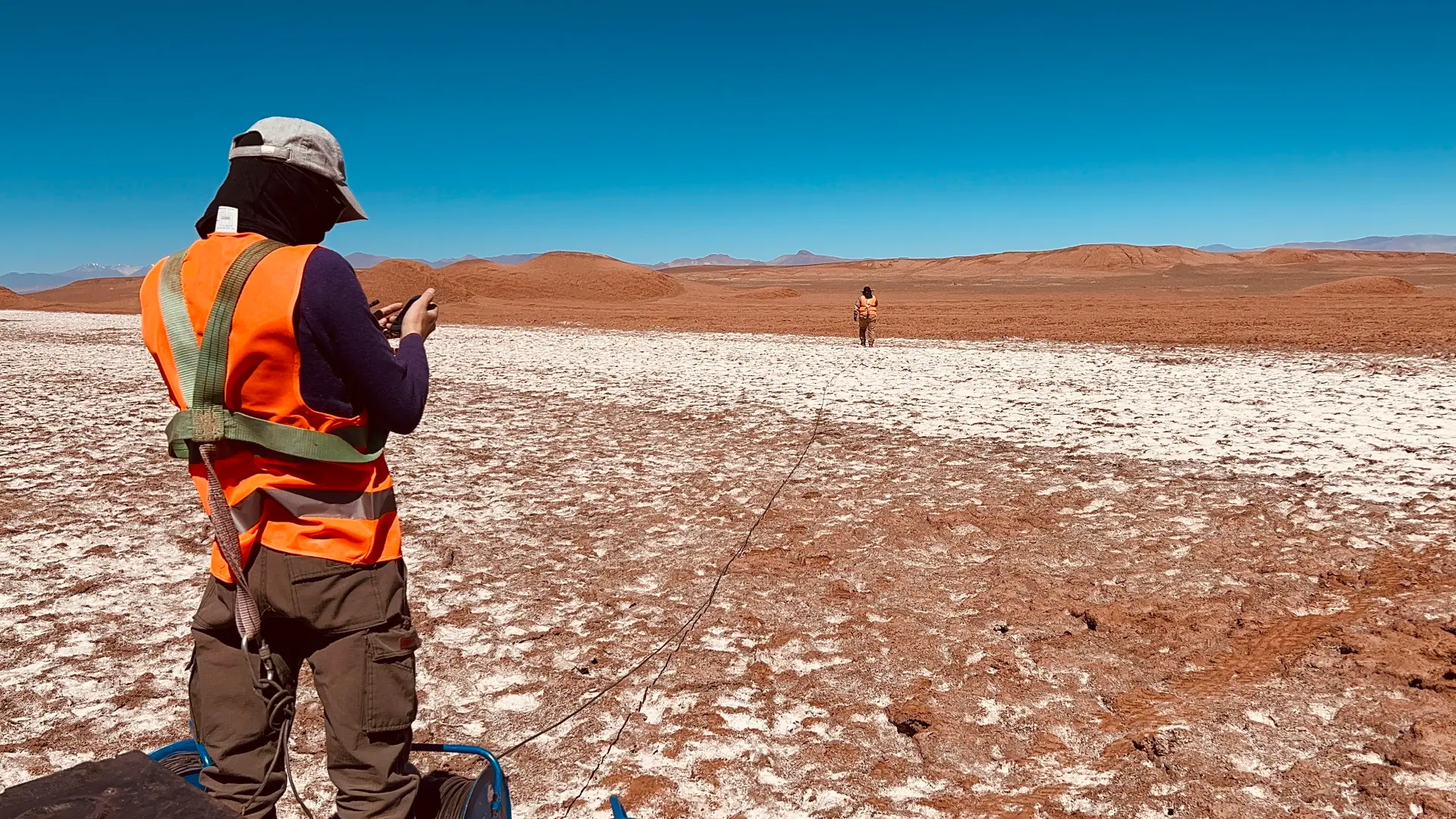 Field technician paying out survey cable across a salt crust in the Puna
