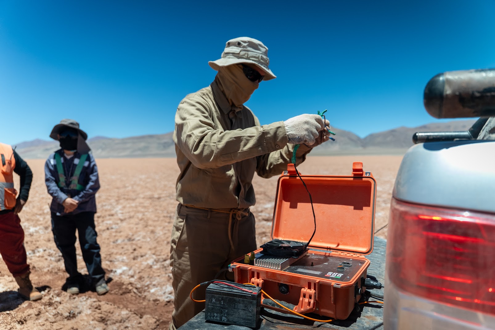 Operator connecting cables to a TEM transmitter unit on a truck bed