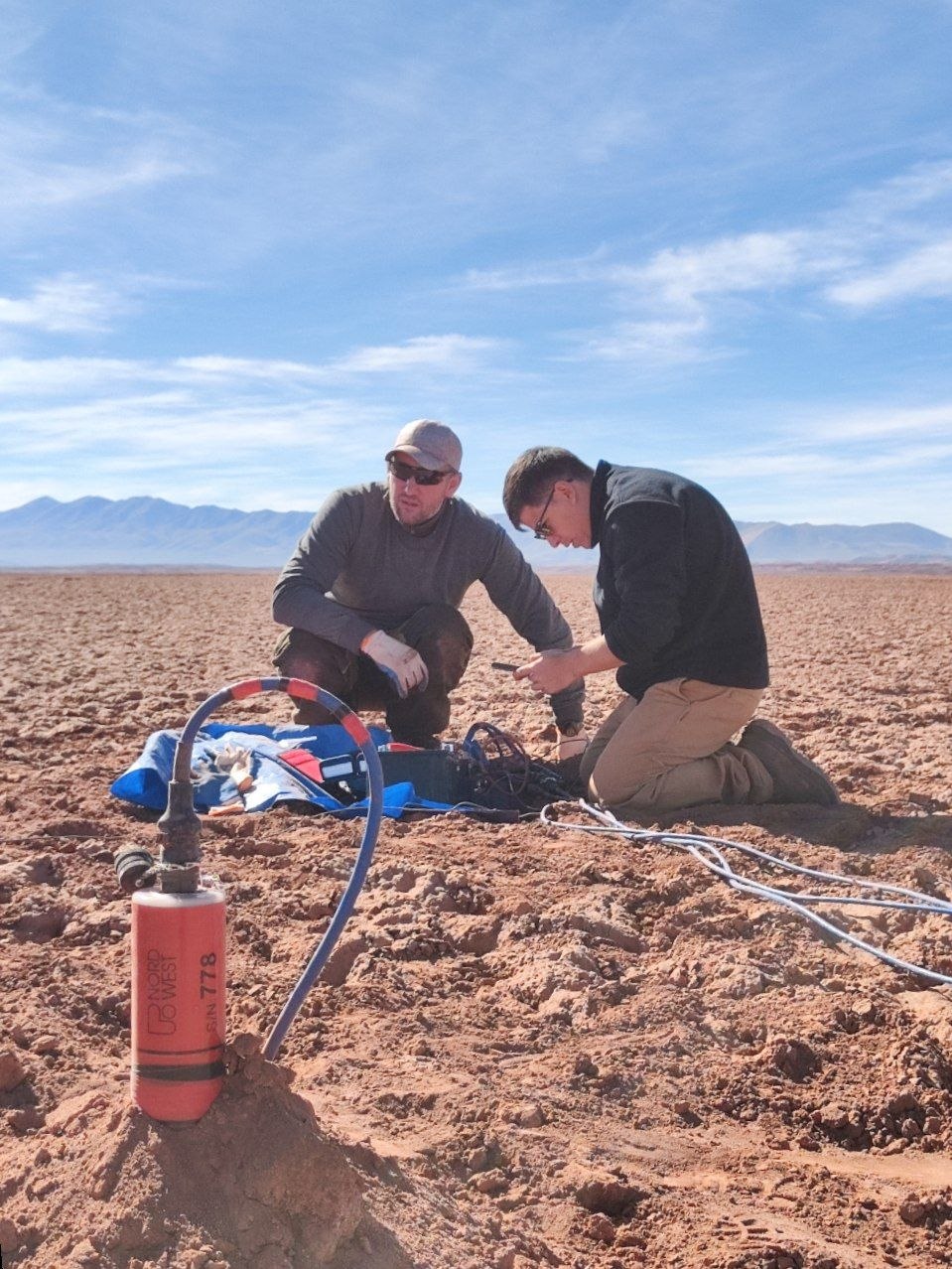 MT acquisition — geophysicists installing a magnetotelluric station on the salar